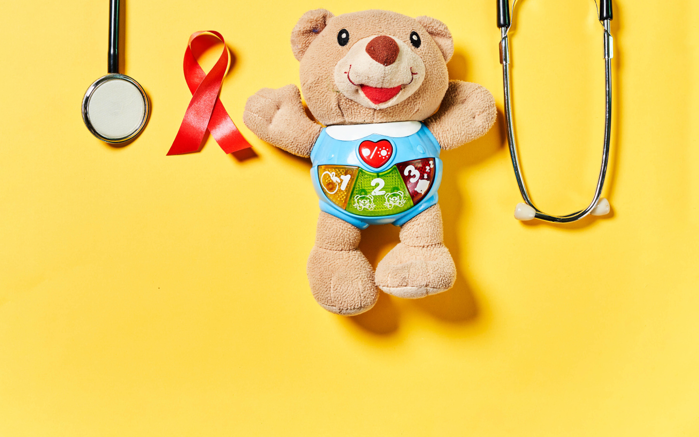 Игрушечный медвежонок с фонендоскопом на желтом фоне 