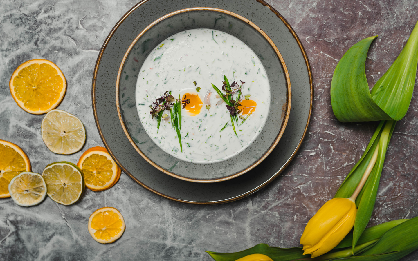 Окрошка на столе с лимонами и тюльпаном