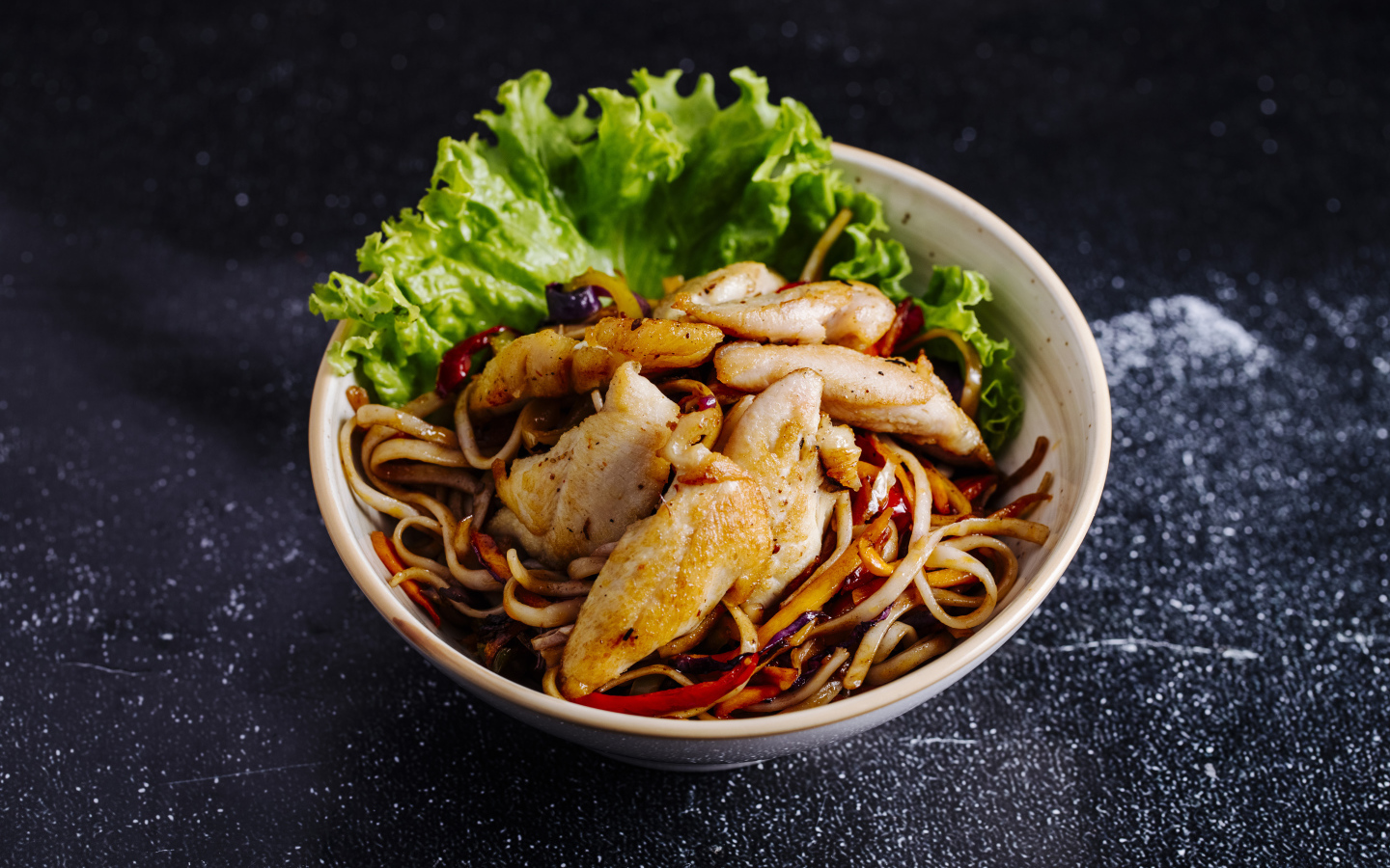 Спагетти с соусом в тарелке с кусочками курицы и листьями салата