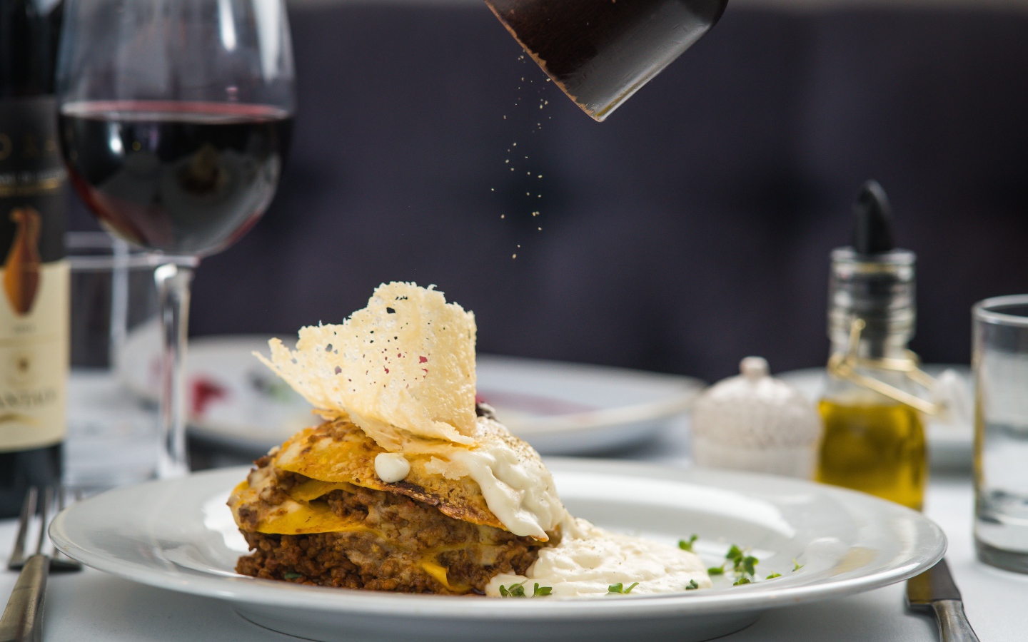 Кусок лазаньи посыпают перцем 