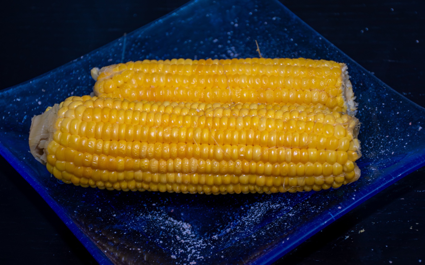 Два желтых початка кукурузы на синей тарелке