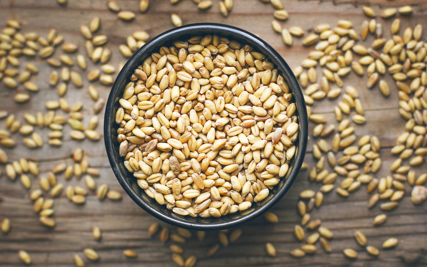 Зерна пшеницы в черной кружке на столе 