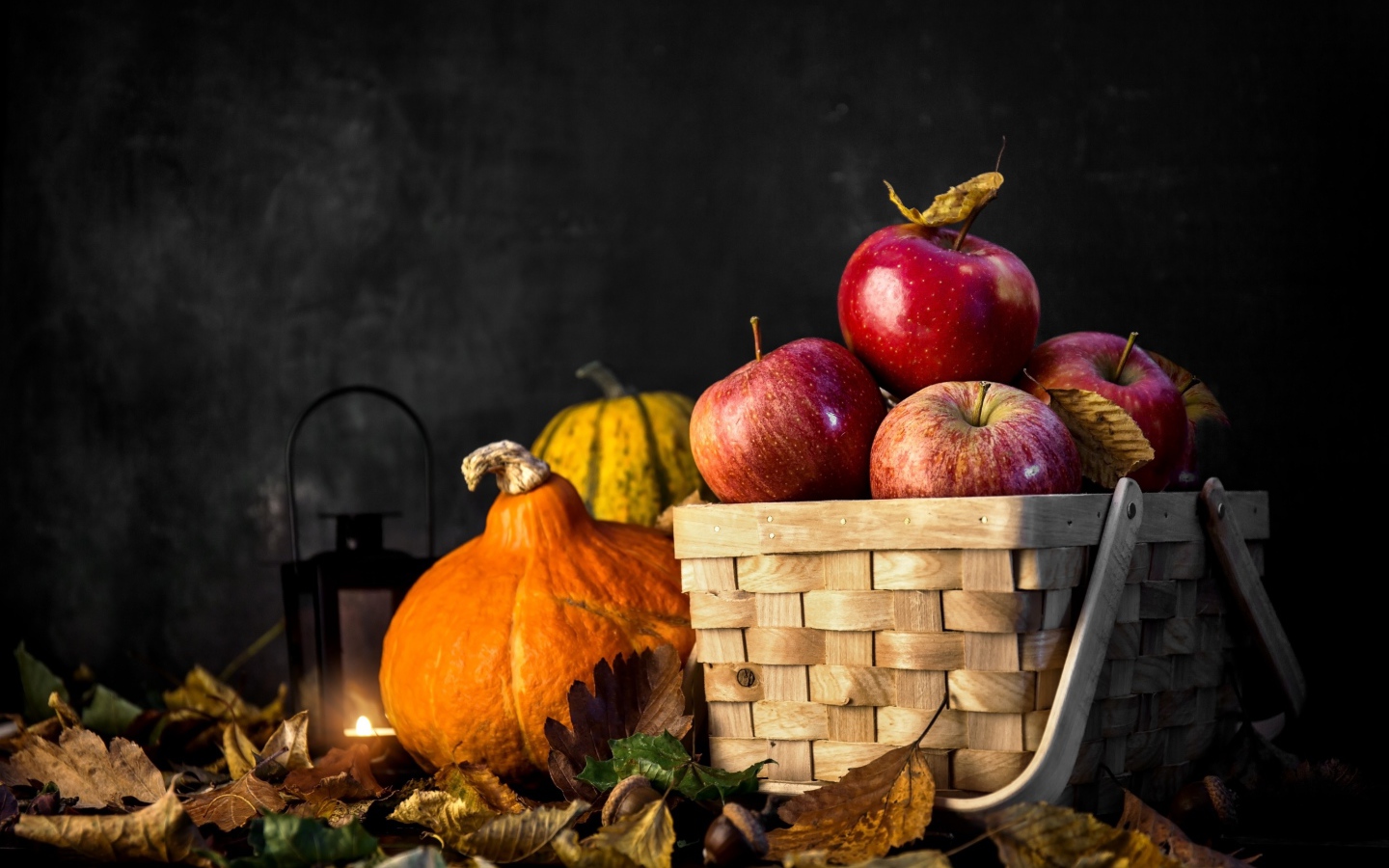 Корзина красных яблок на столе с тыквой