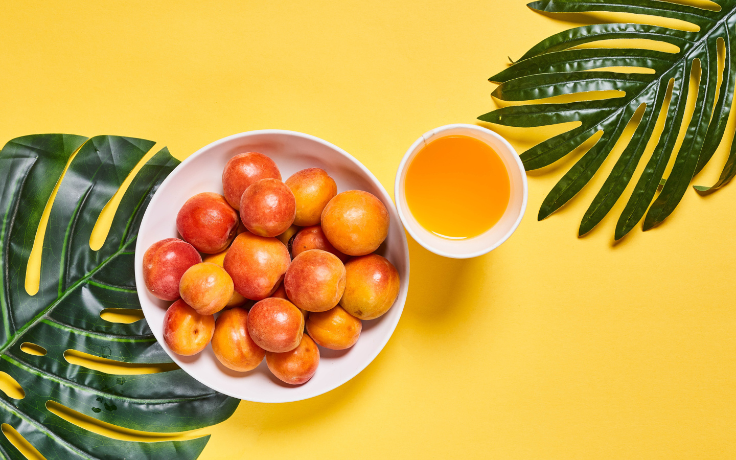 Вкусные спелые абрикосы с зелеными листьями на желтом фоне