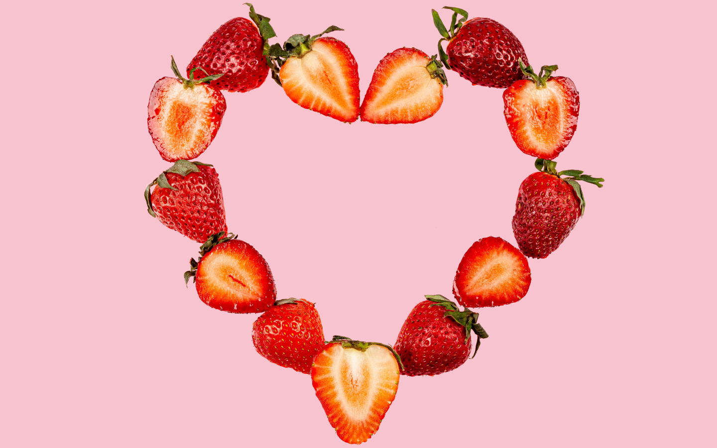 Сердце из клубники на розовом фоне 