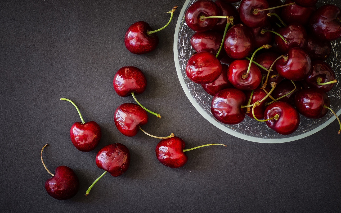 Красные черешни в миске на сером фоне