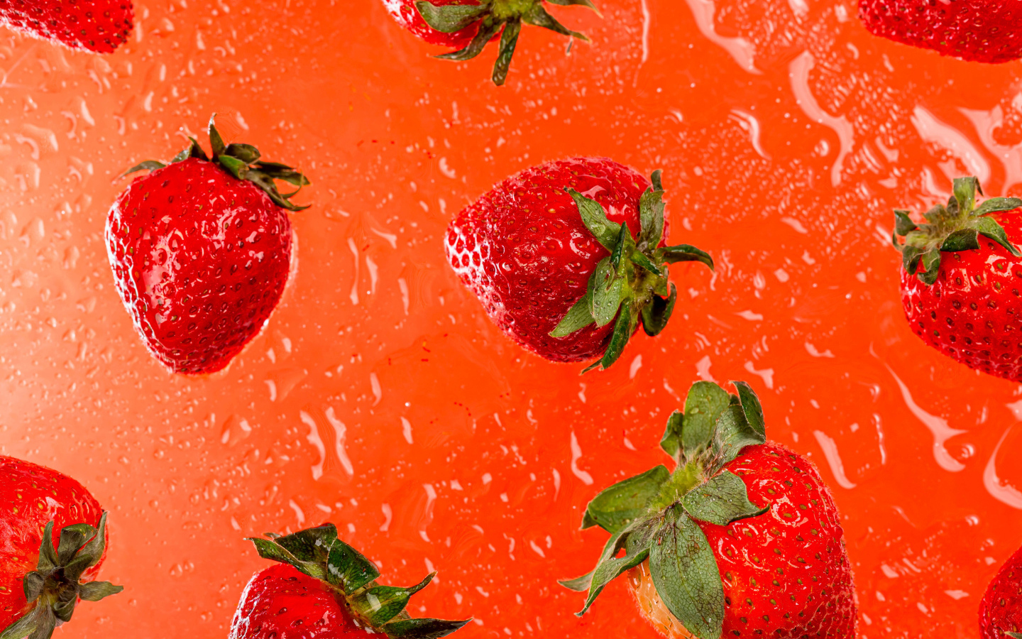 Красная клубника в воде на оранжевом фоне 