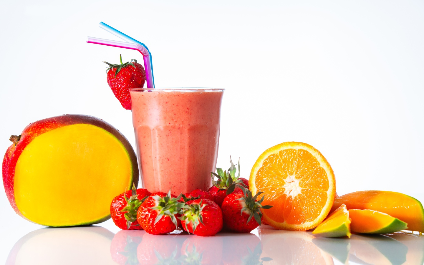 Спелое манго с клубникой и апельсином на столе со смузи