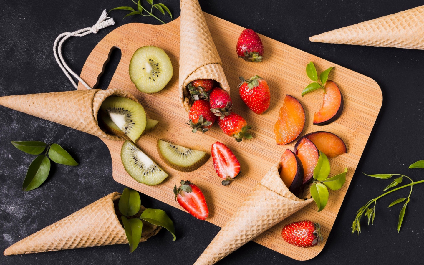 Вафельные рожки с ягодами и фруктами на доске 