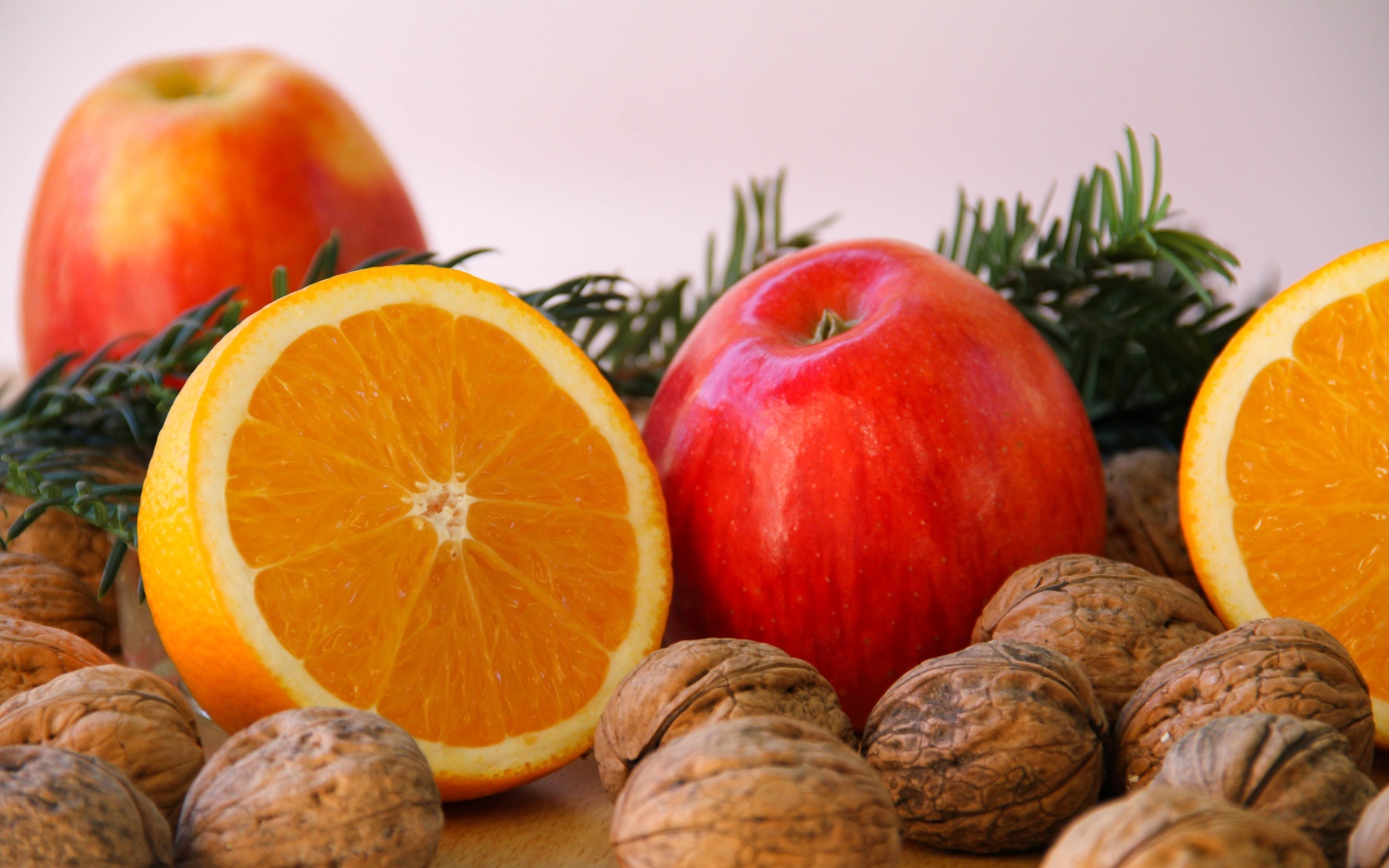 Грецкие орехи с апельсинами и яблоками на сером фоне 