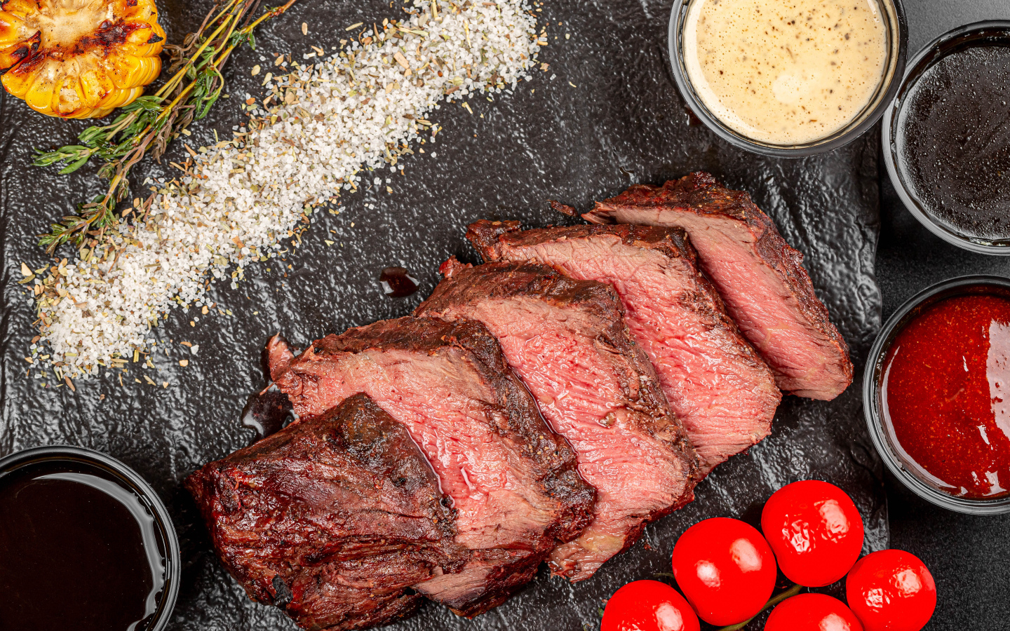 Мясо с помидорами и соусами на доске 