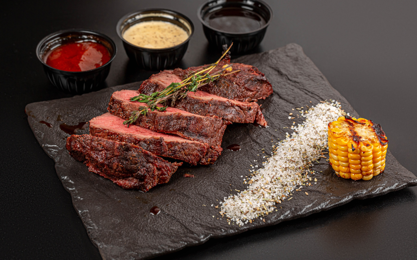 Кусок запеченного мяса на доске с кукурузой и специями 