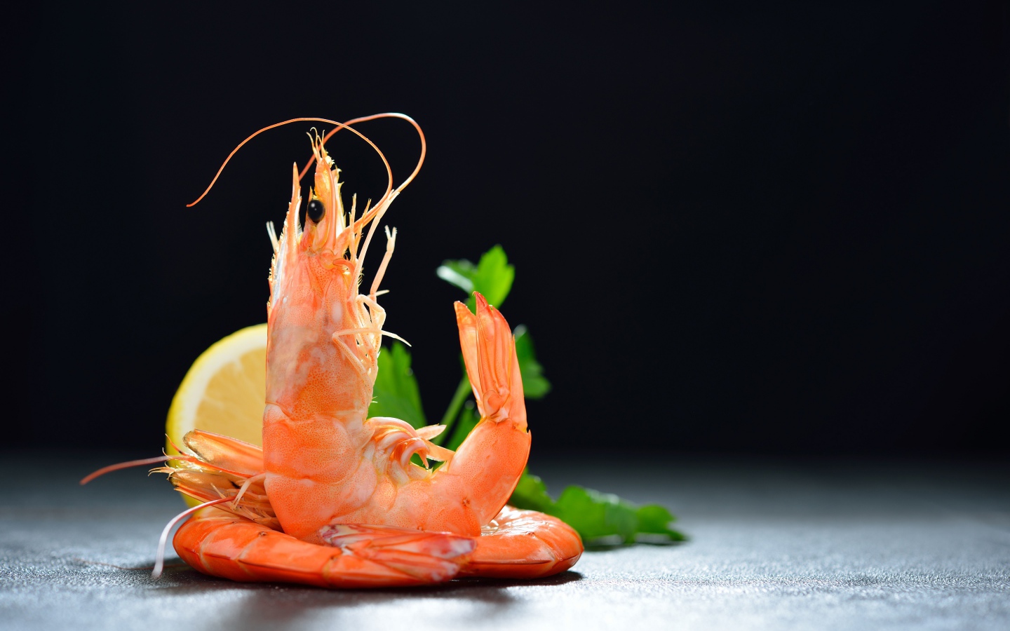 Вареные креветки с лимоном на черном фоне