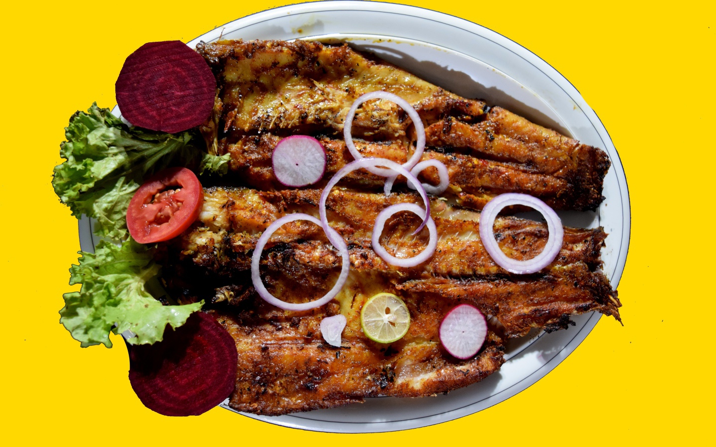 Жареная рыба с листьями салата, помидорами и свеклой на желтом фоне