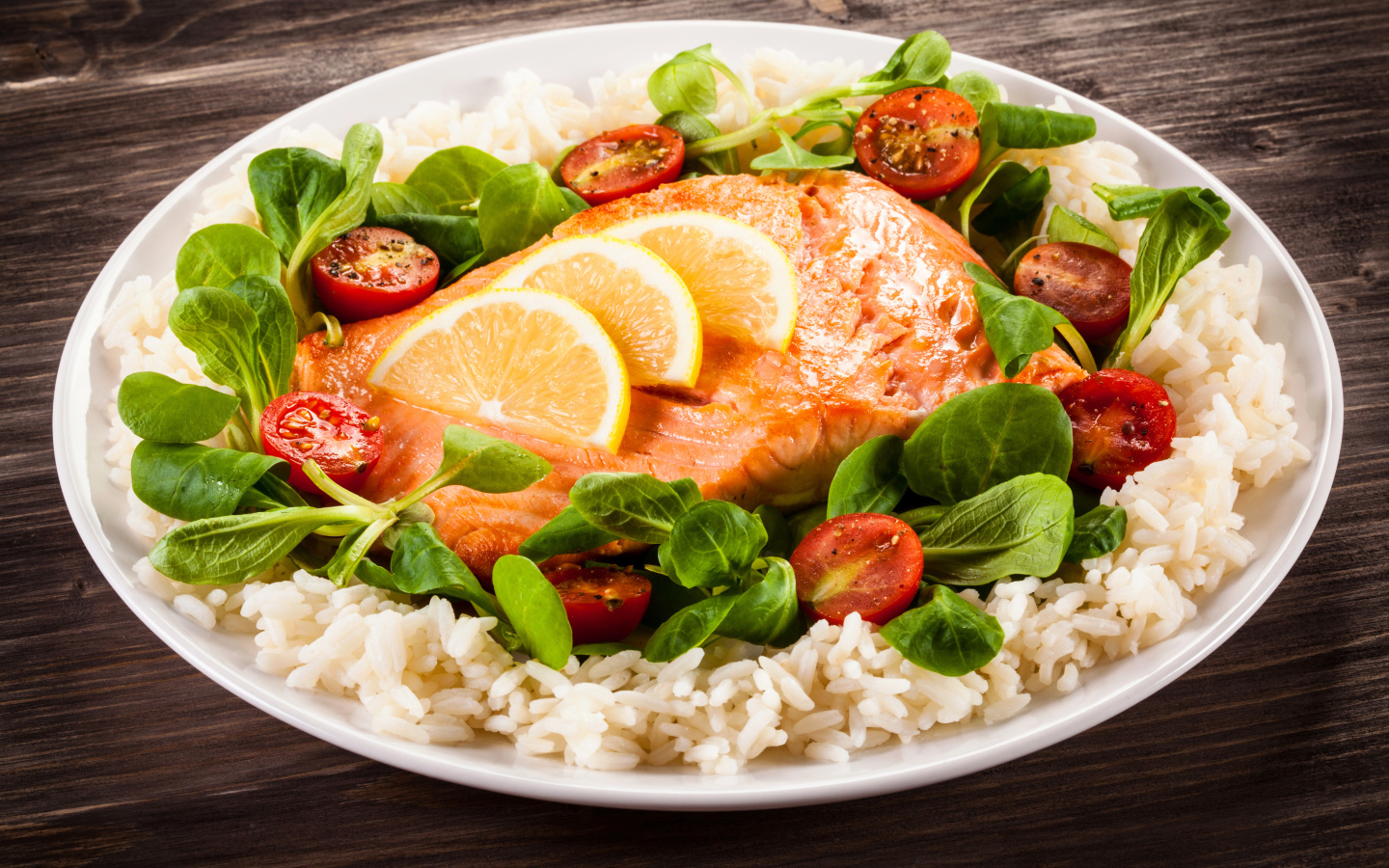 Кусок рыбы на тарелке с помидорами, рисом и листьями базилика 
