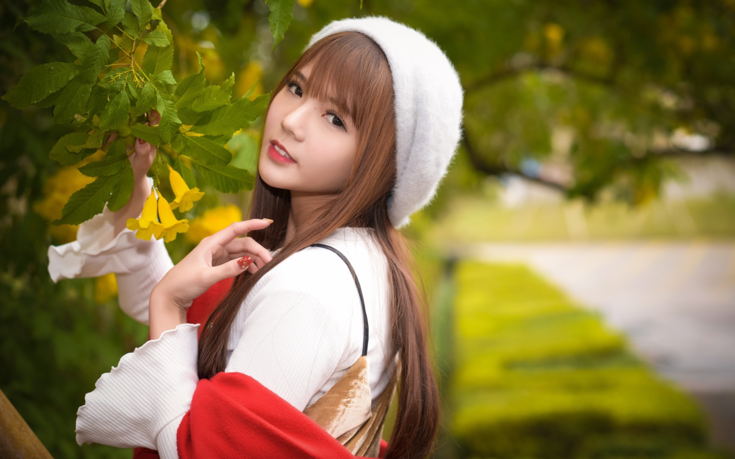 Девушка в берете стоит у куста с желтыми цветами