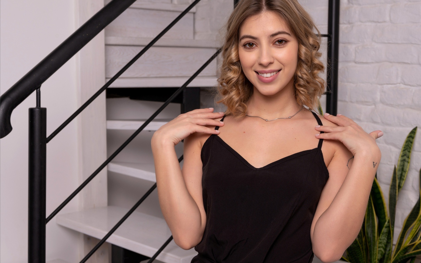 Девушка в черном платье стоит у ступеней