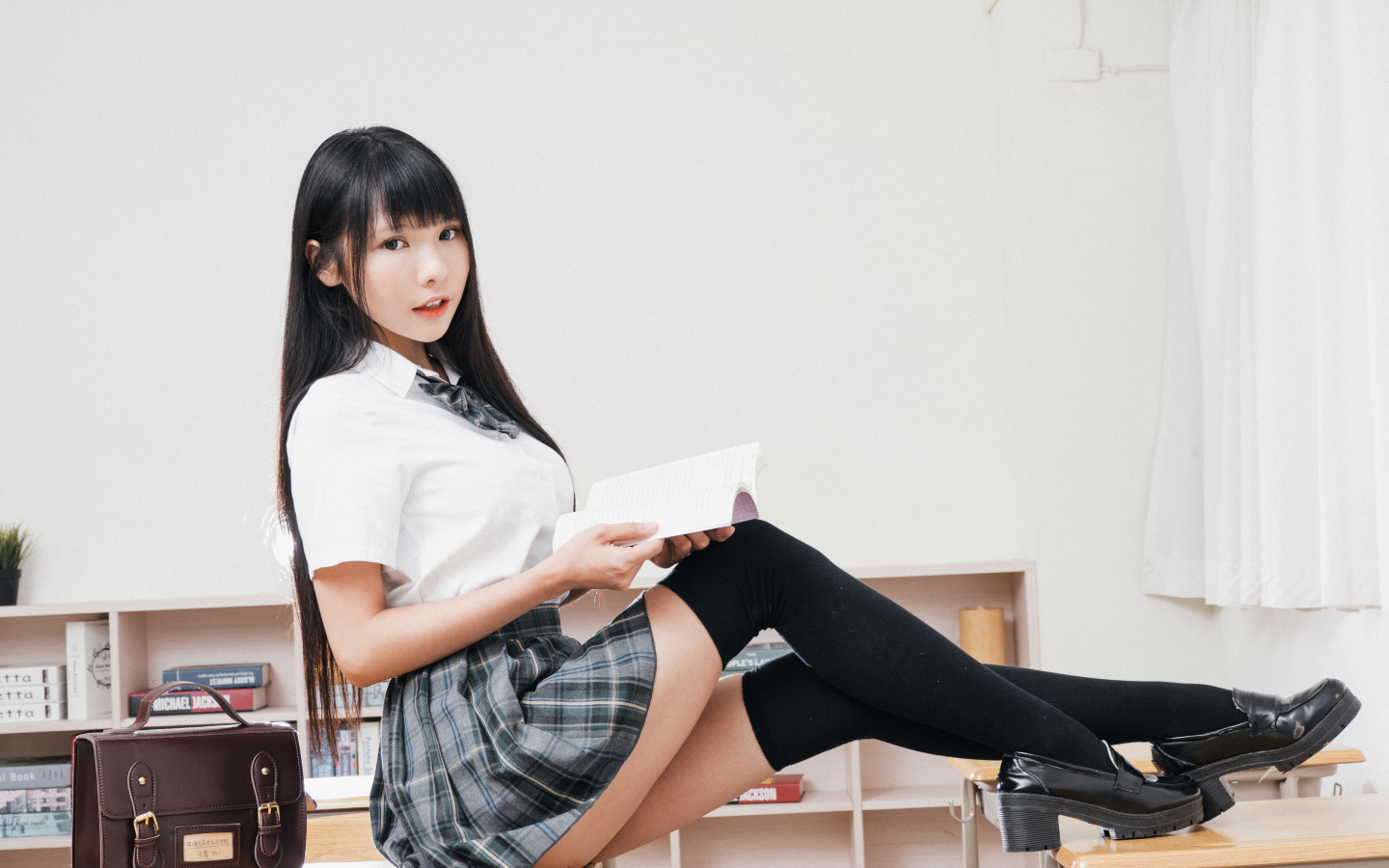 Девушка азиатка в костюме школьницы на парте 