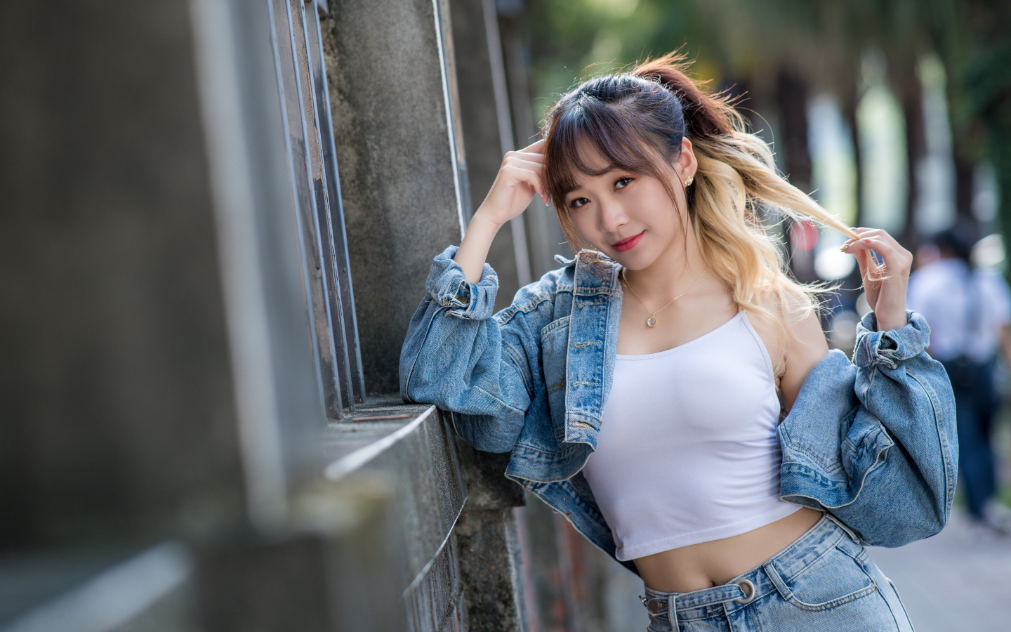 Девушка азиатка в джинсовой куртке у забора 
