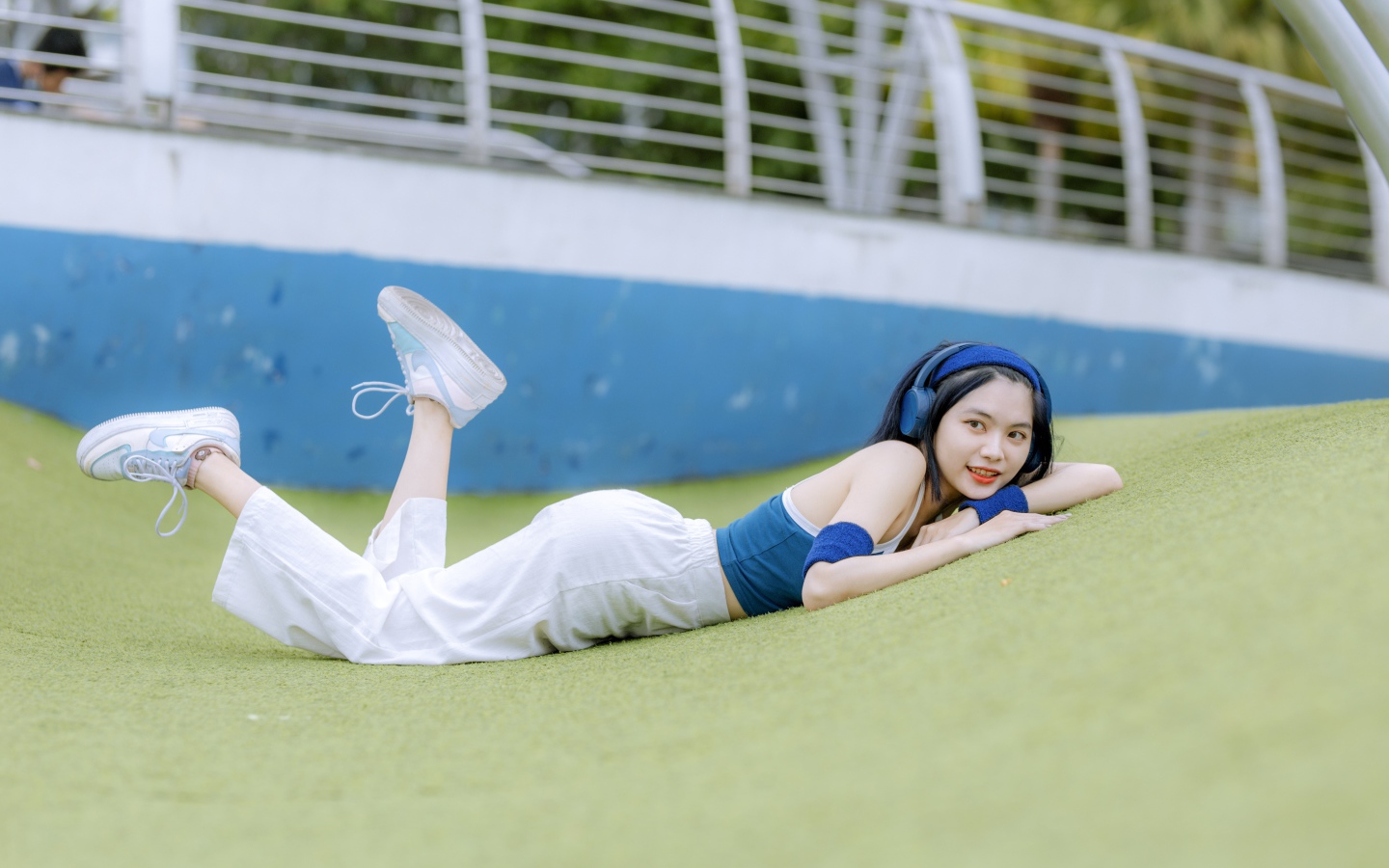 Девушка азиатка в наушниках лежит на полу 