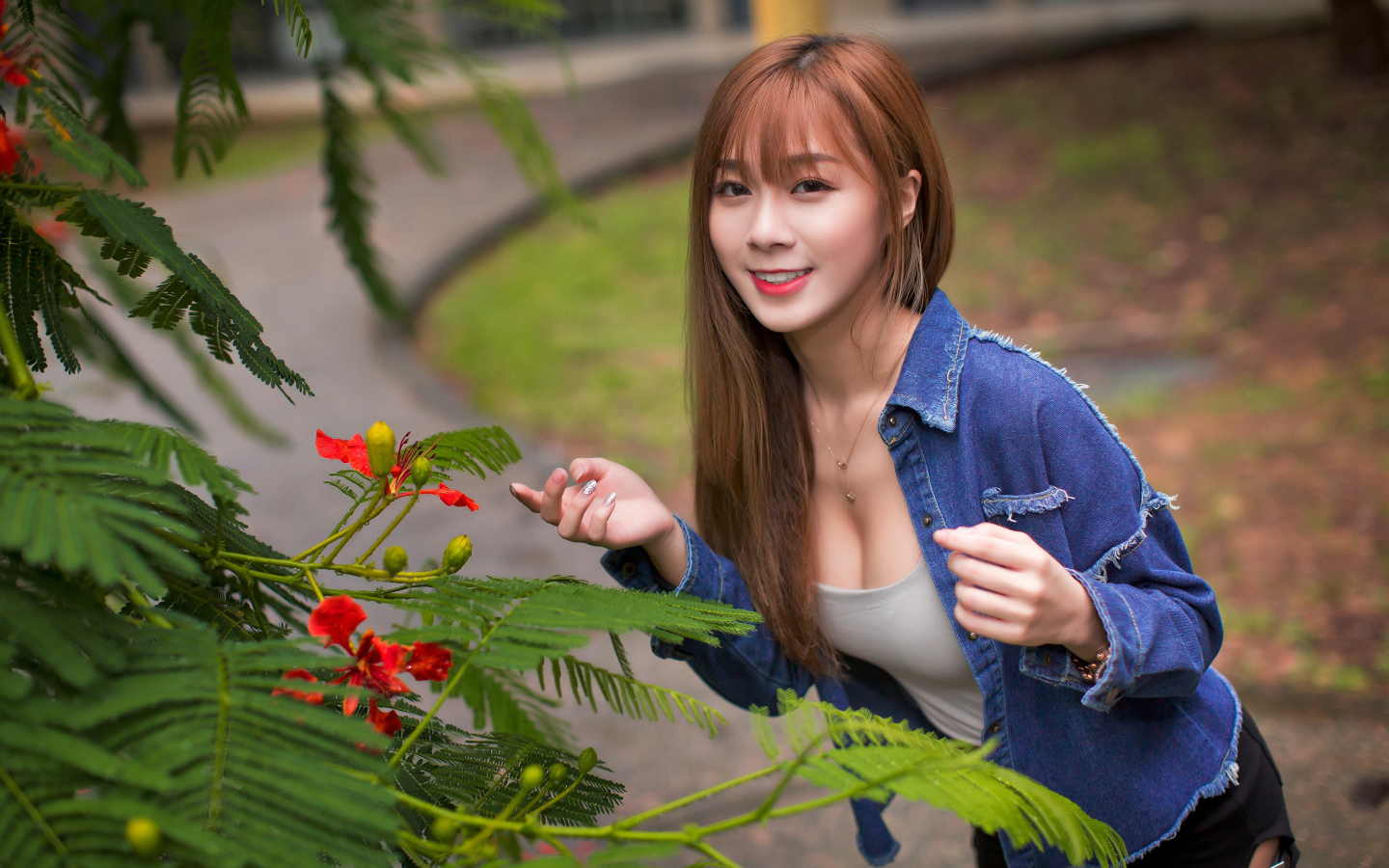 Девушка азиатка стоит у растения с зелеными листьями