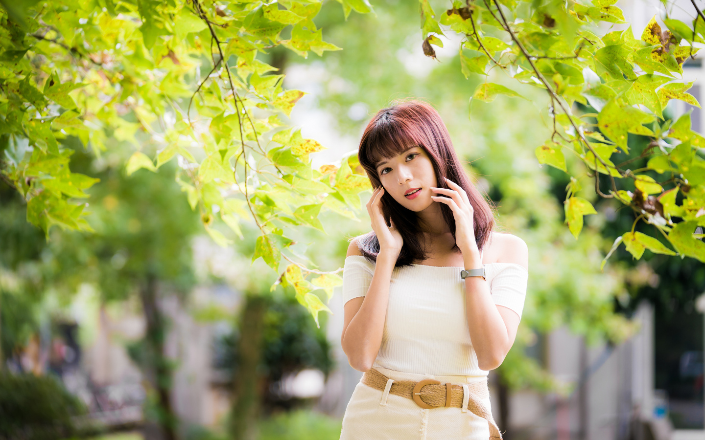 Красивая азиатка в белом платье у дерева 