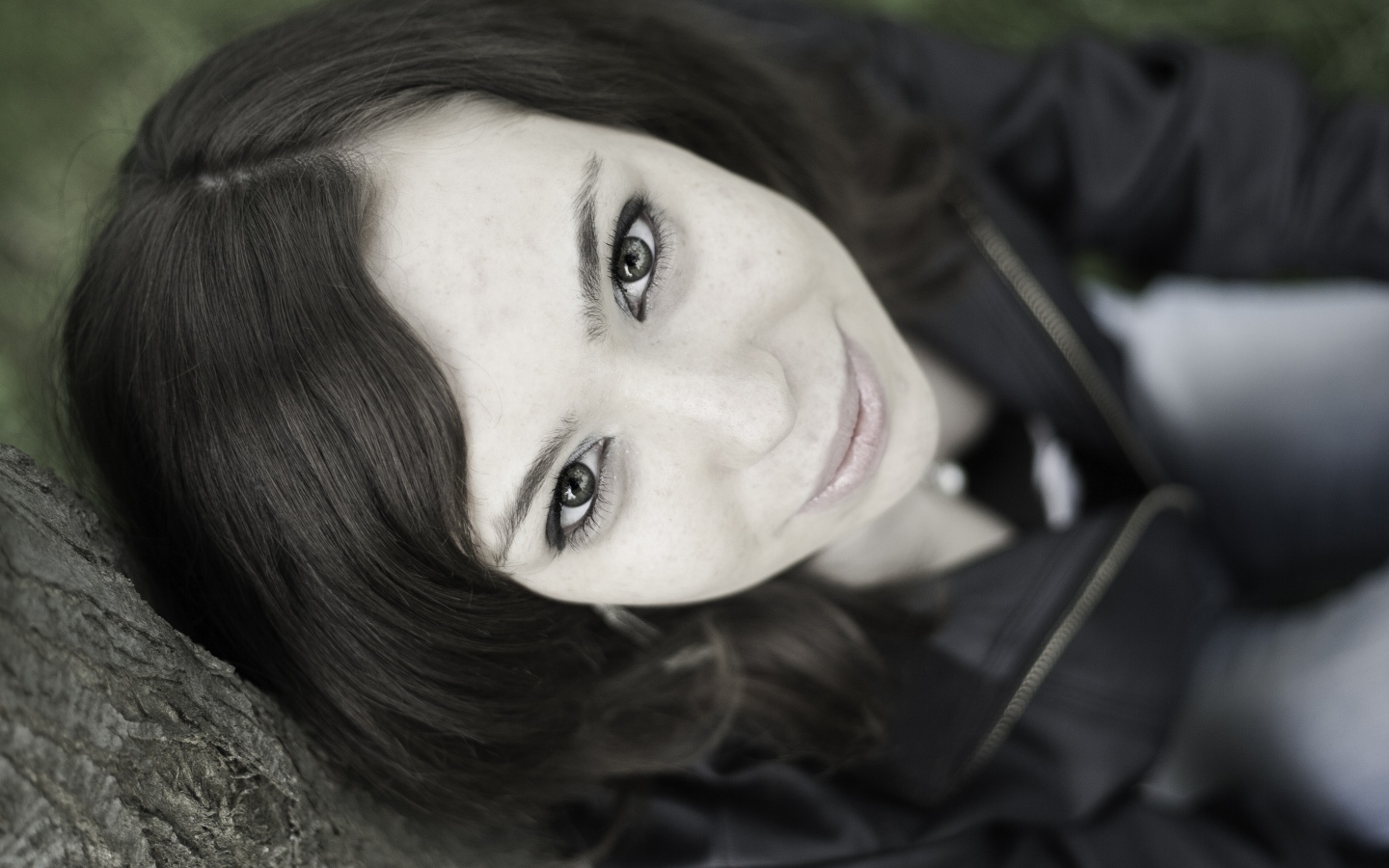 Красивая девушка смотрит вверх сидя под деревом  