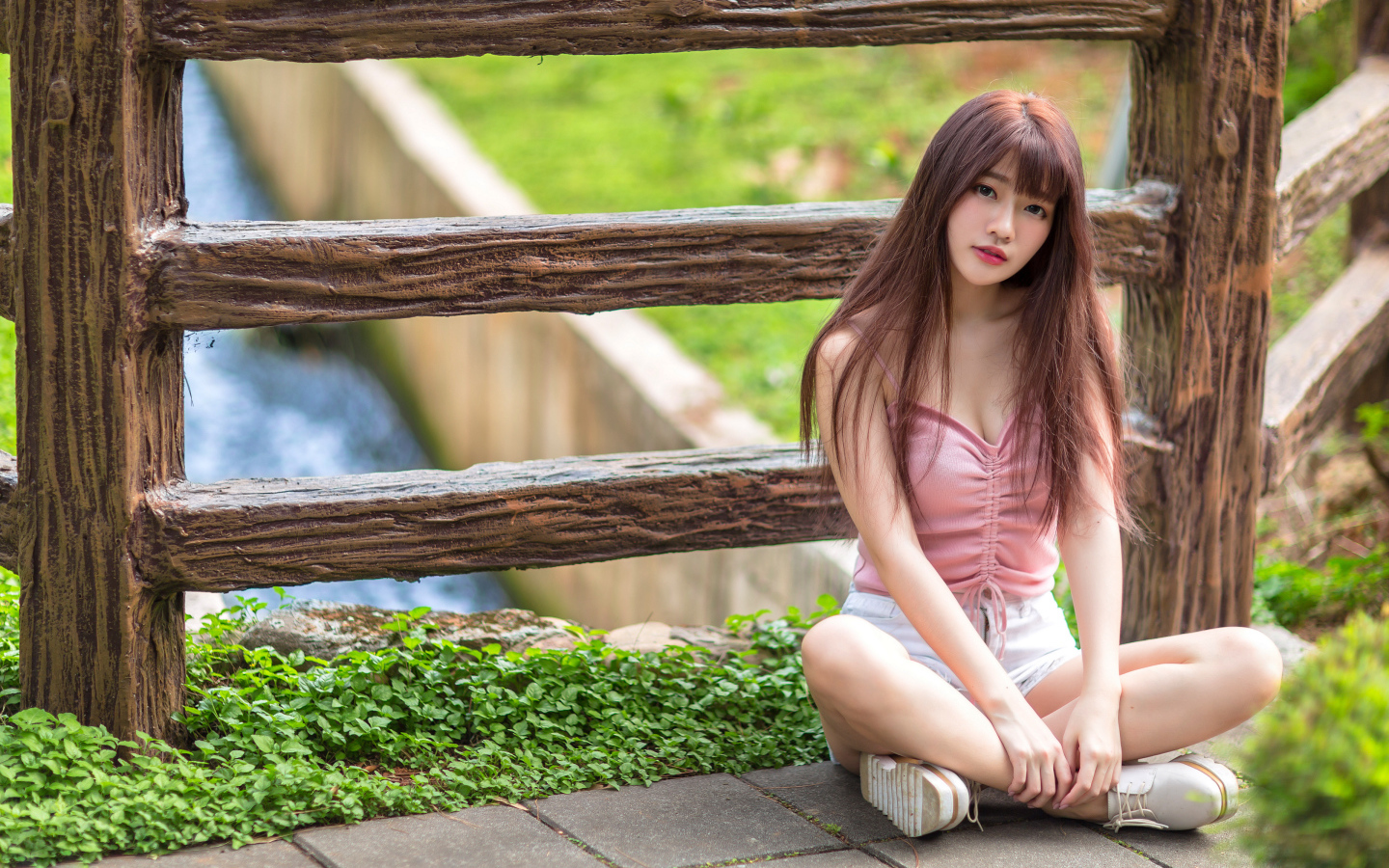 Длинноволосая азиатка сидит у забора 