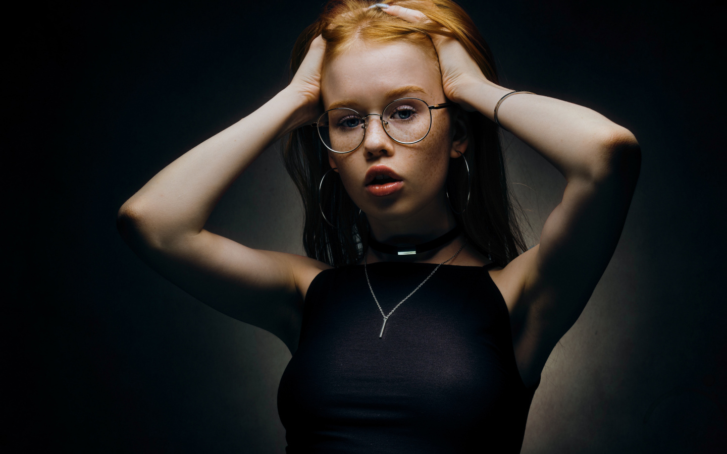 Рыжеволосая девушка в очках на черном фоне