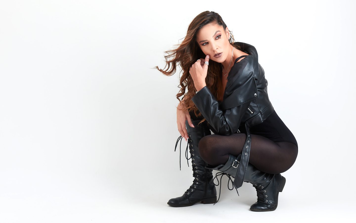 Девушка рокерша в черной куртке на белом фоне 