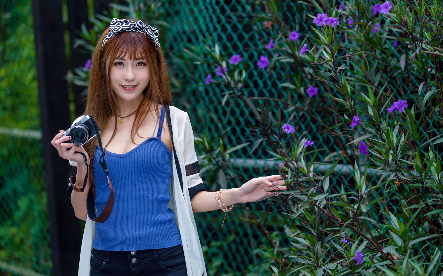 Улыбающаяся девушка фотограф стоит у сетки 