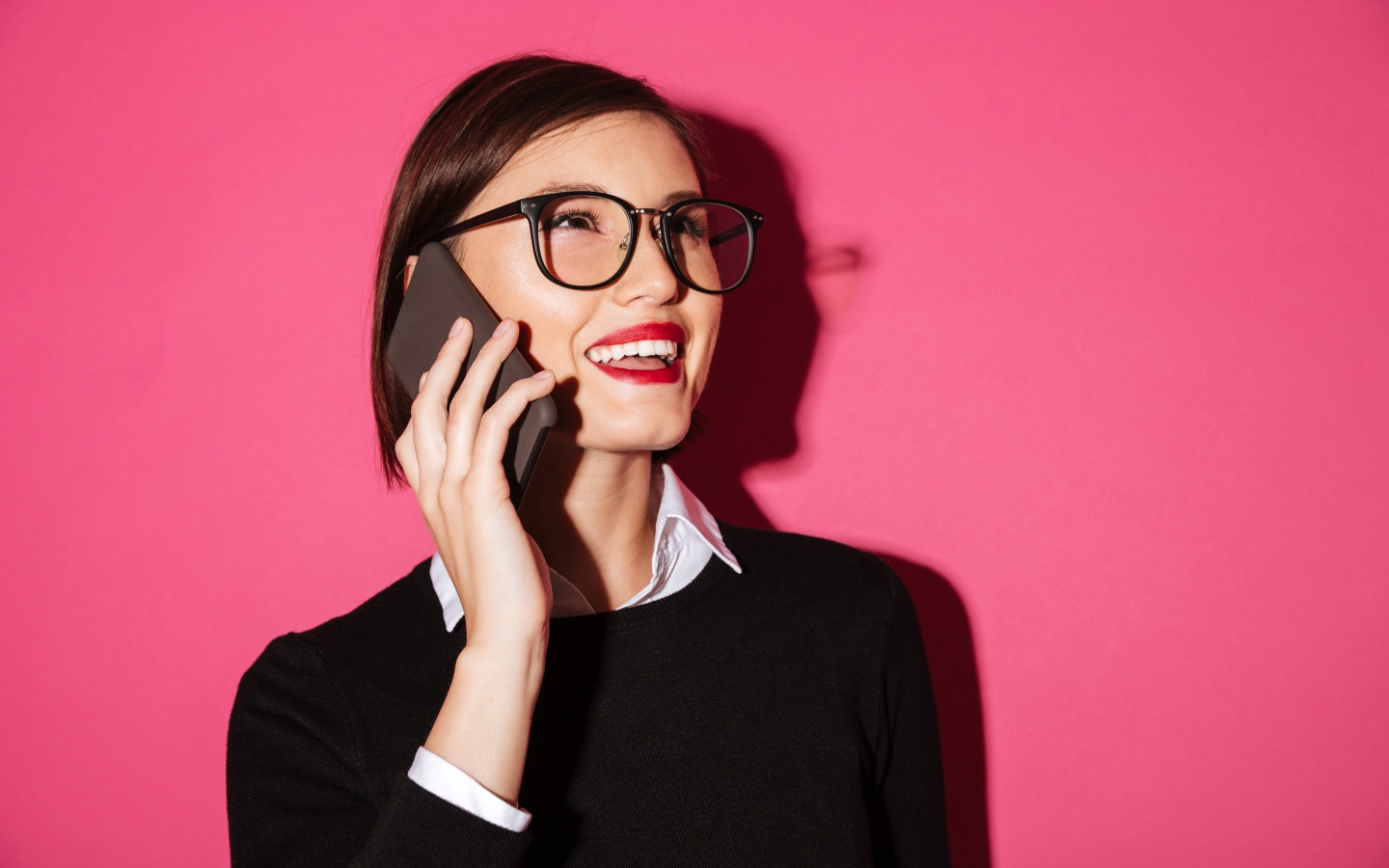 Улыбающаяся девушка с телефоном на розовом фоне