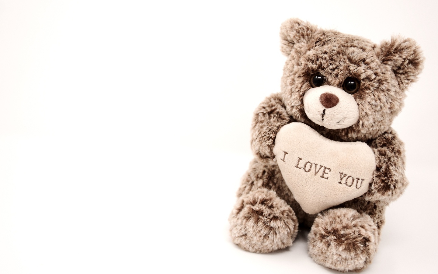 Меховая игрушка медвежонок с сердцем на белом фоне