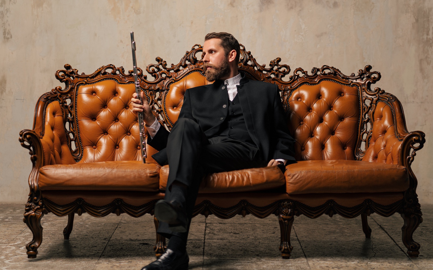 Солидный мужчина в костюме сидит на диване