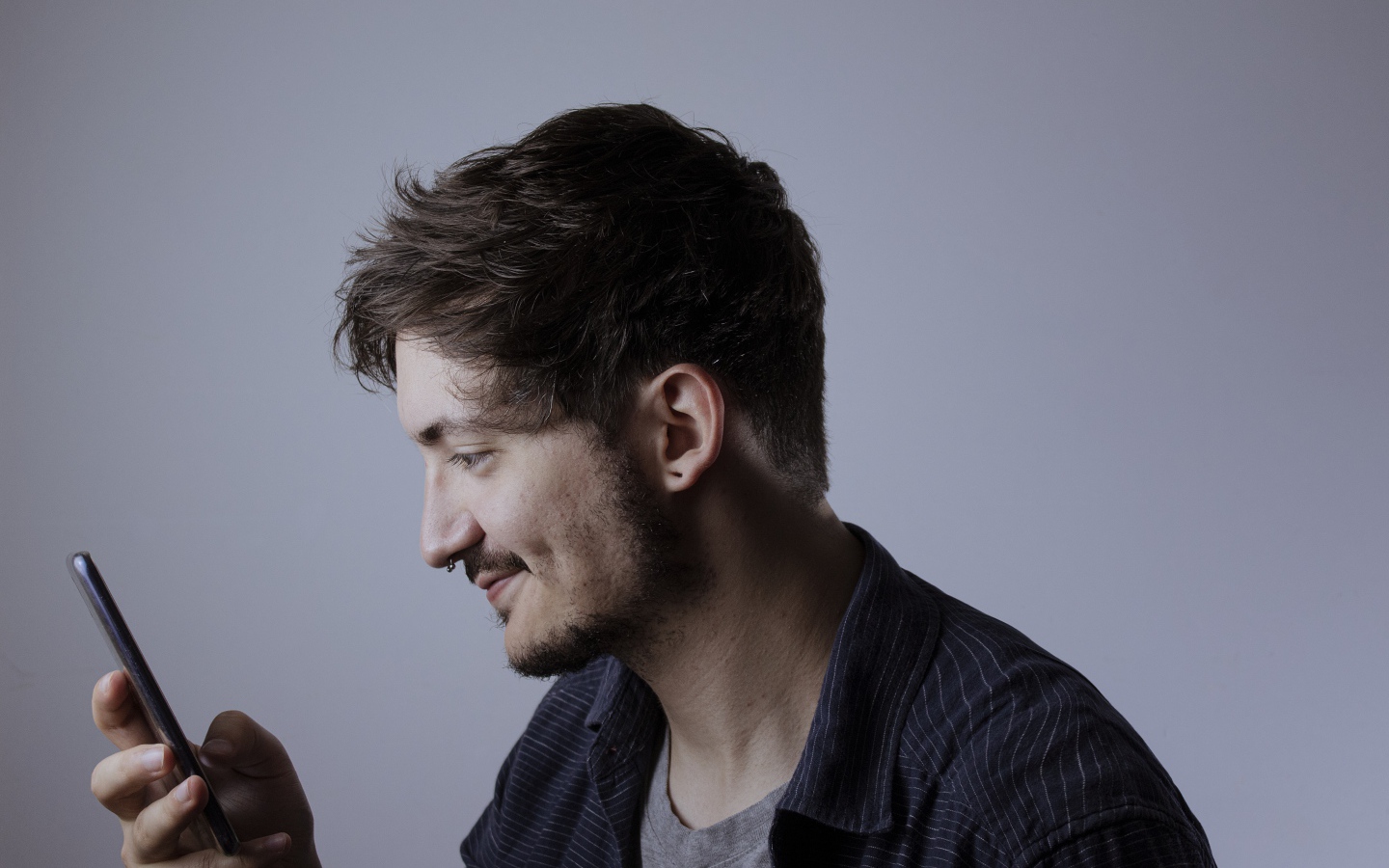 Мужчина с телефоном в руке на сером фоне 