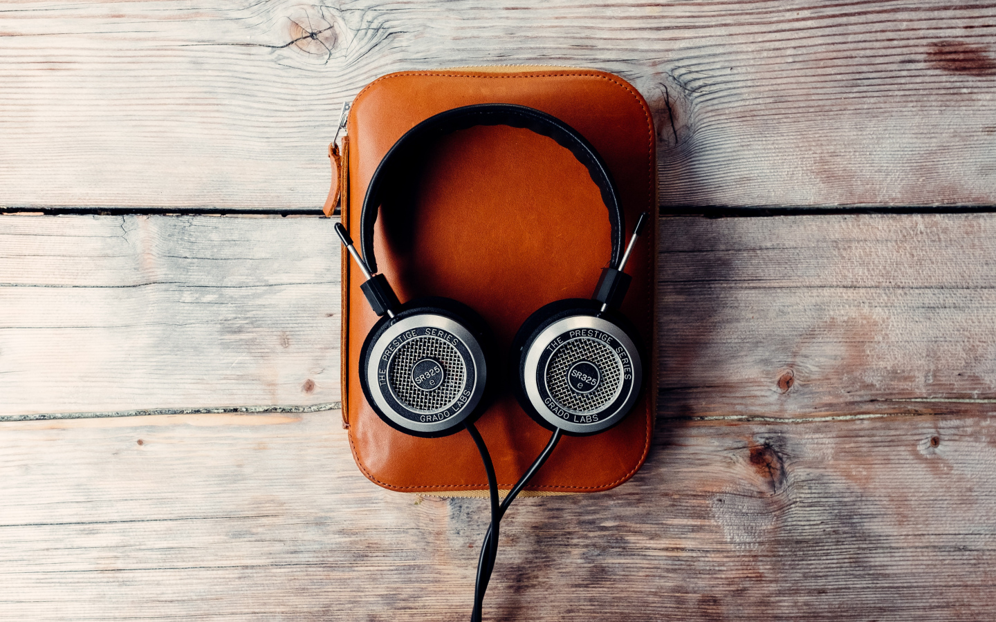 Наушники и плеер в чехле на деревянном столе