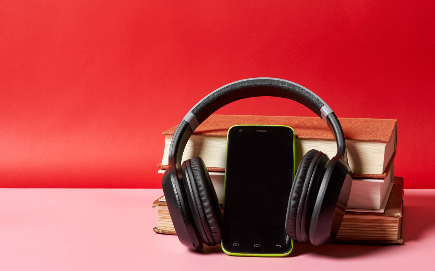 Смартфон, наушники и книги на красном фоне