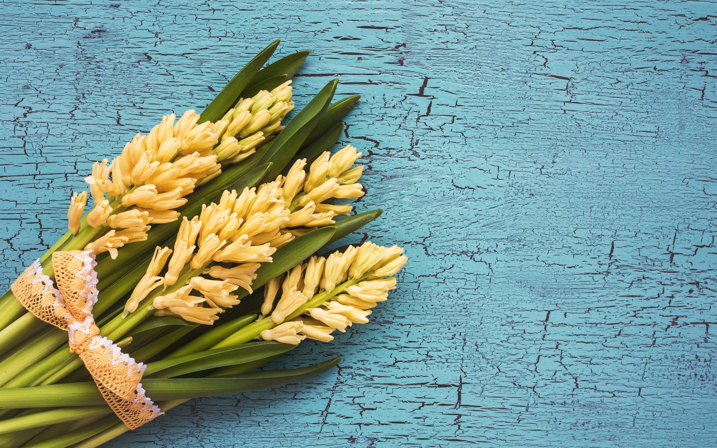 Букет желтых гиацинтов с зелеными листьями на голубом фоне