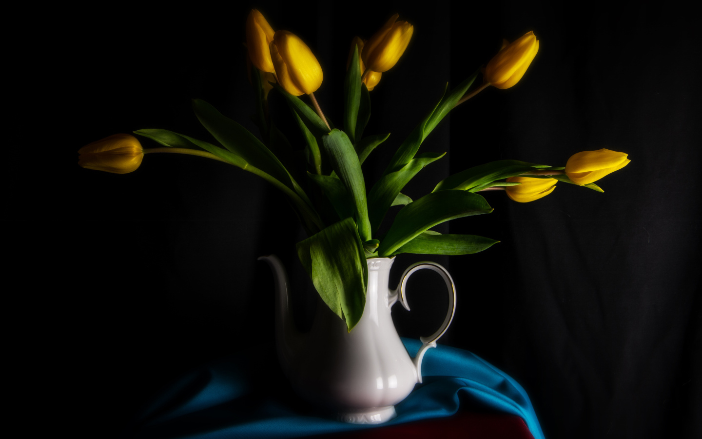 Желтые тюльпаны в белой вазе на черном фоне