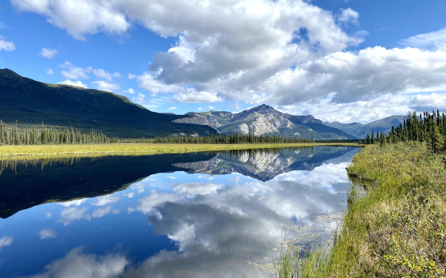Небо с белыми облаками отражается в реке 