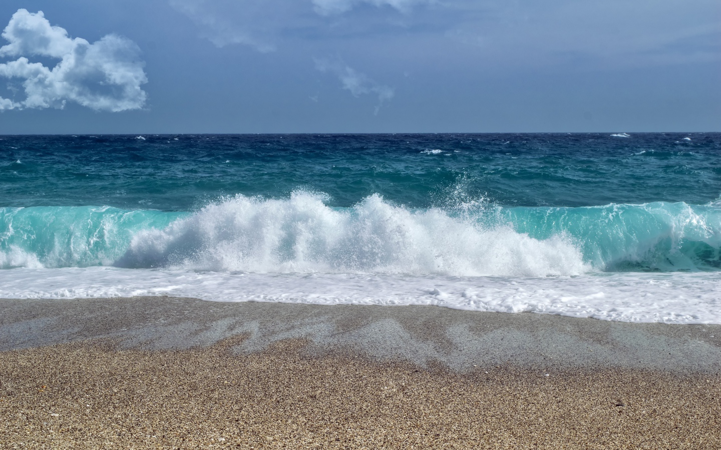 Blue ocean waves on wet sand