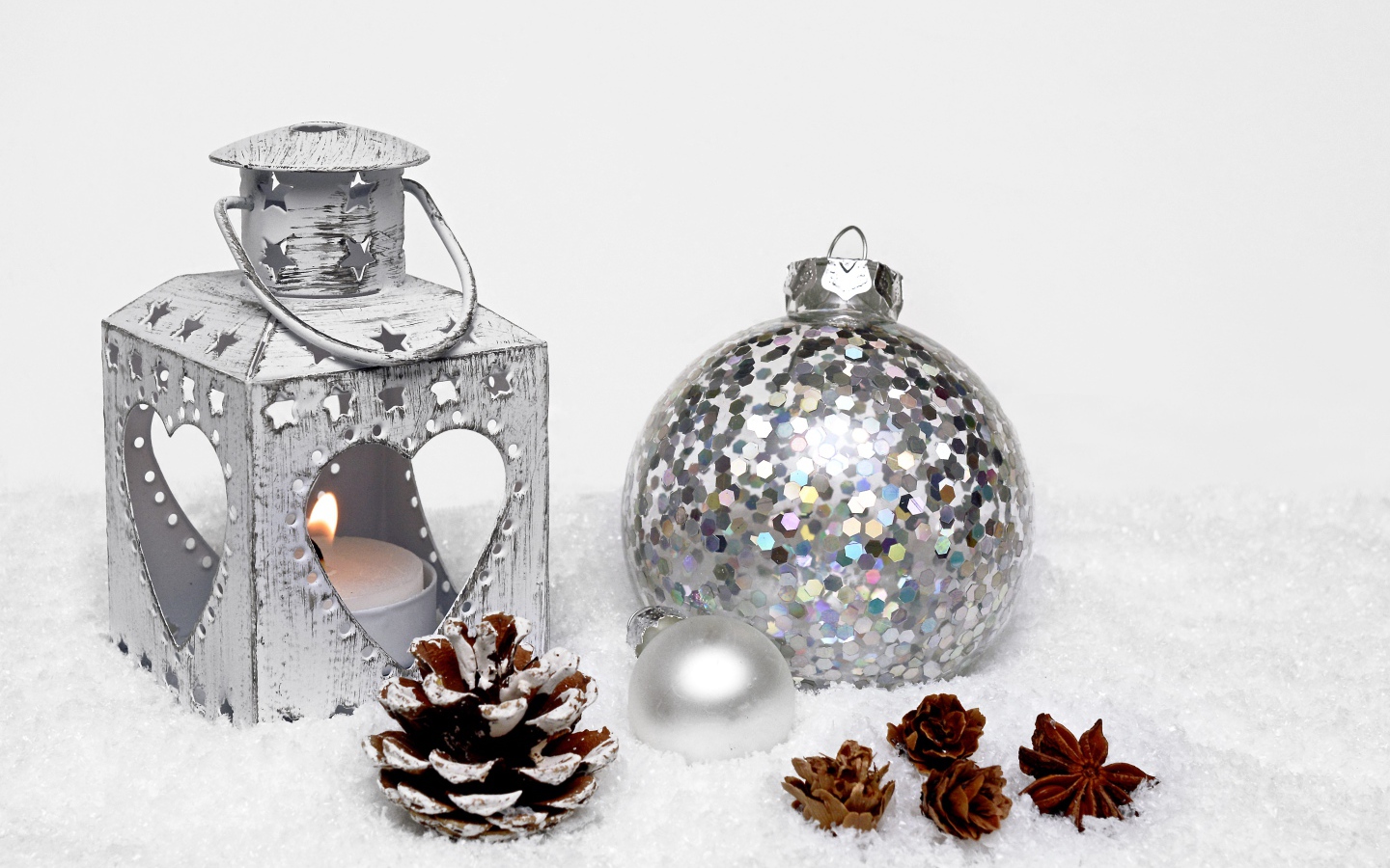 Фонарик и елочный шар с шишками на снегу