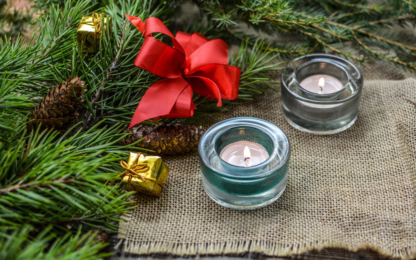 Две зажженные свечи, еловая ветка и красный бант на рождество 