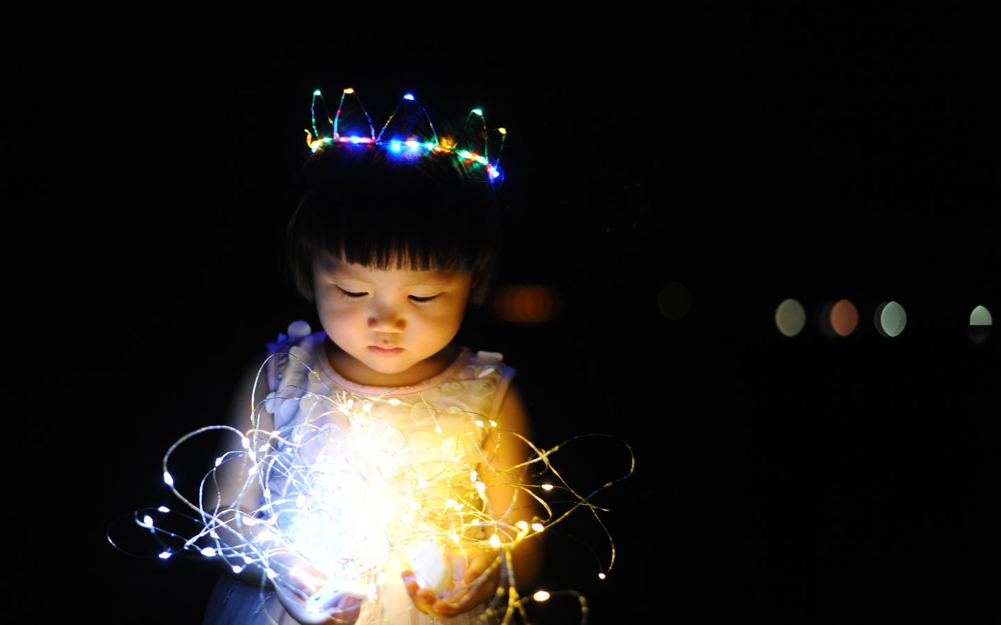 Маленькая девочка азиатка с гирляндой в руках на черном фоне