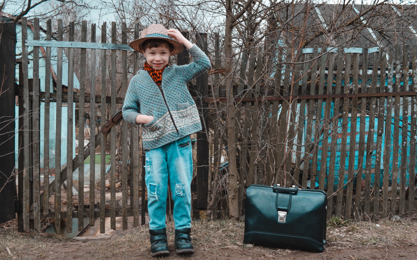 Маленький мальчик с чемоданом у забора