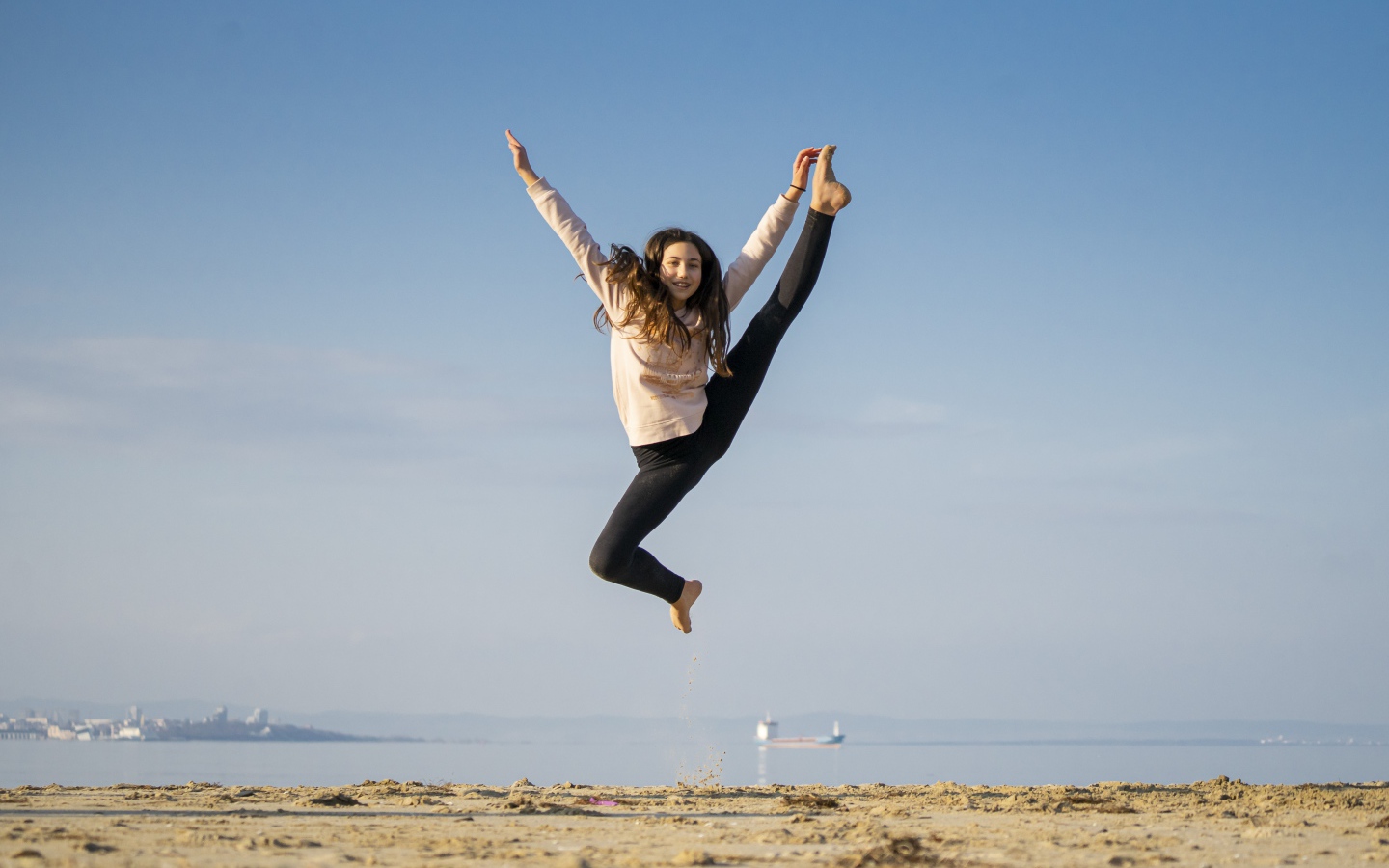 Маленькая девочка гимнастка на песке