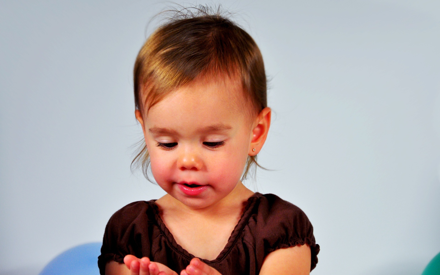 Маленькая девочка смотрит на руки на сером 