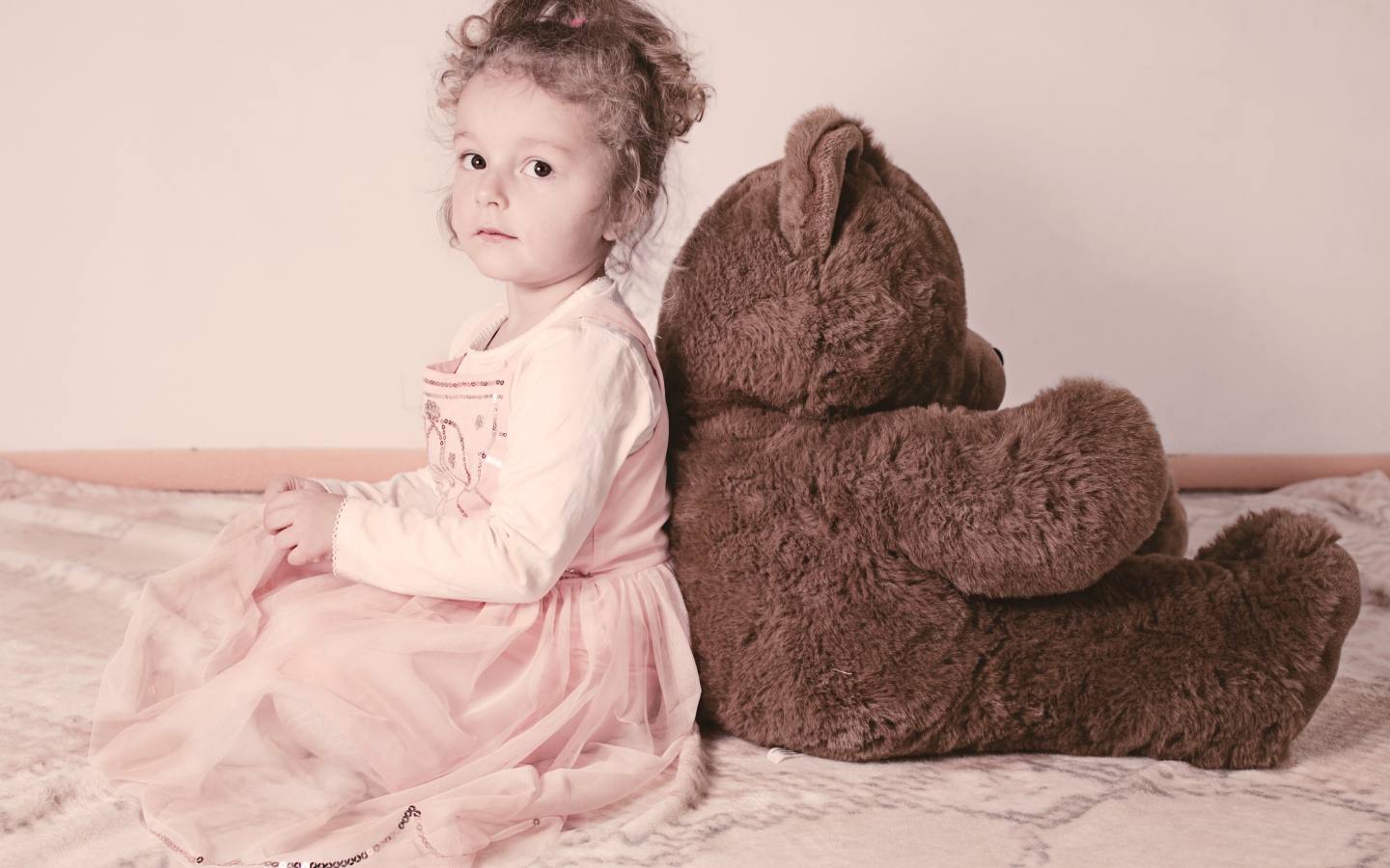 Маленькая девочка сидит с большим медведем