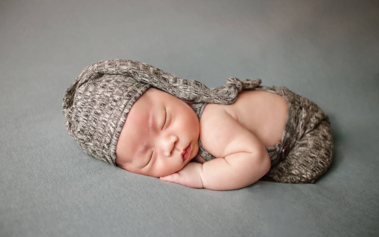 Маленький новорожденный ребенок на сером фоне