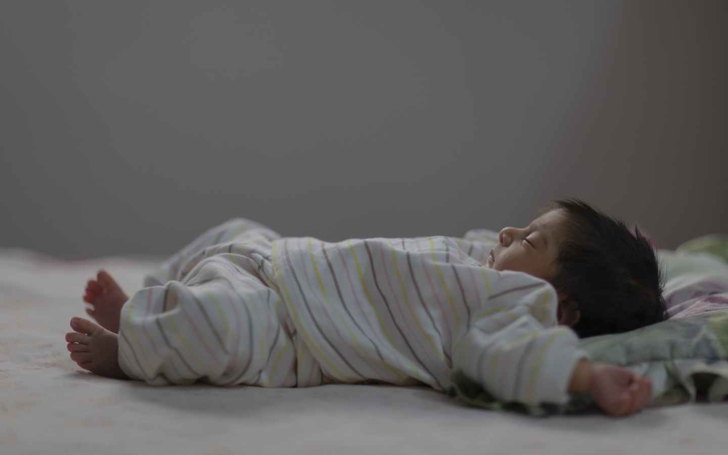 Маленький спящий грудной ребенок на кровати 